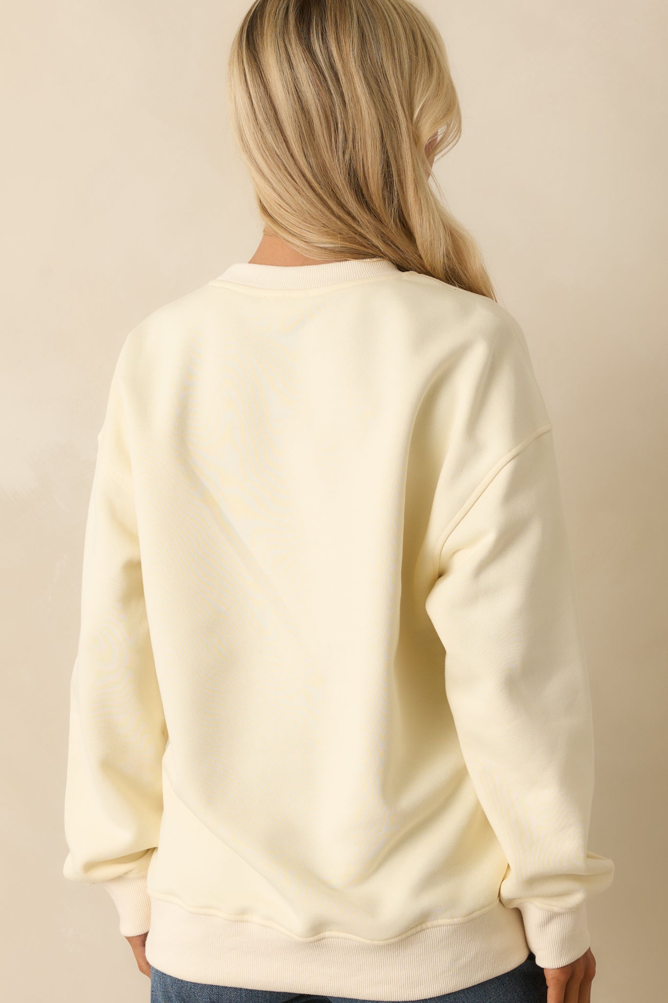 Back view of plain ivory cotton sweatshirt with relaxed drop-shoulder cut and ribbed hem finish.