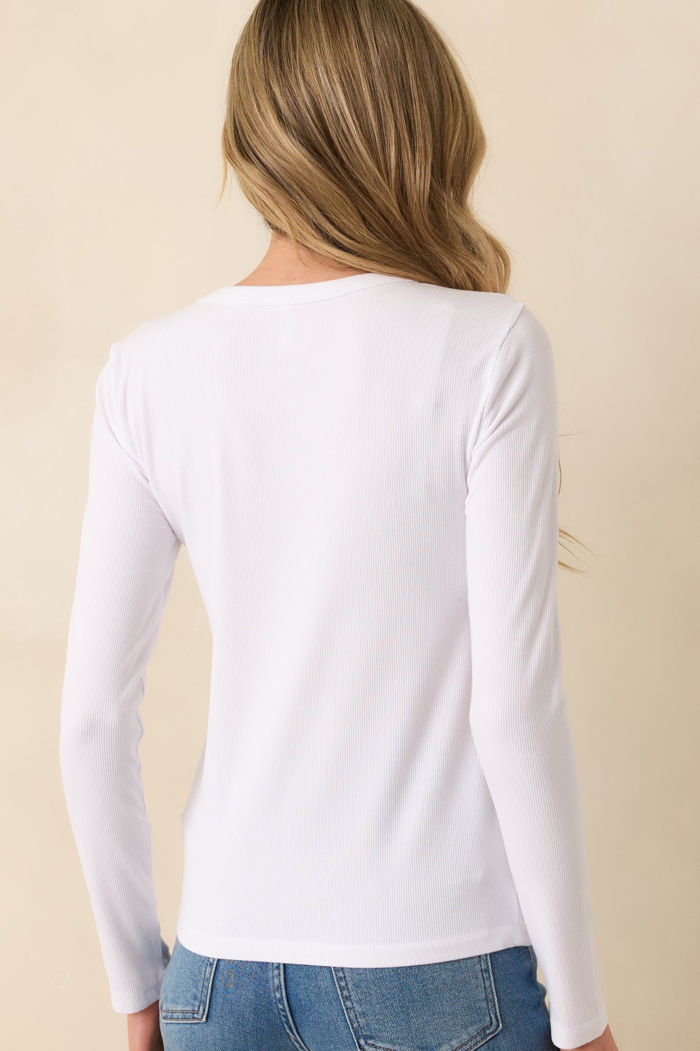 A view from behind of the ivory top, displaying the simple back design and how the long sleeves and relaxed fit continue around.