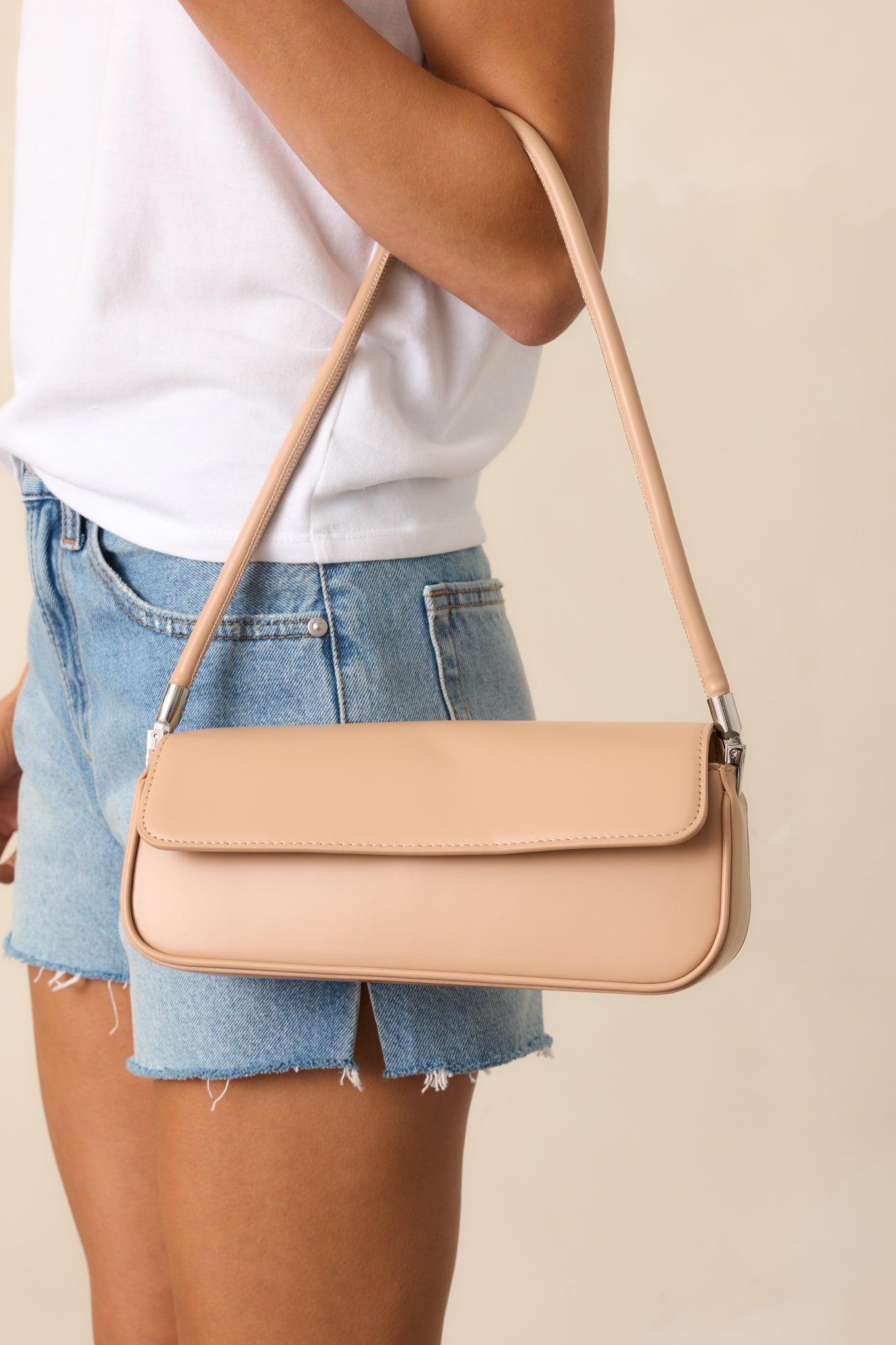 A close-up of the structured shoulder strap, highlighting its sturdy design and smooth beige material.