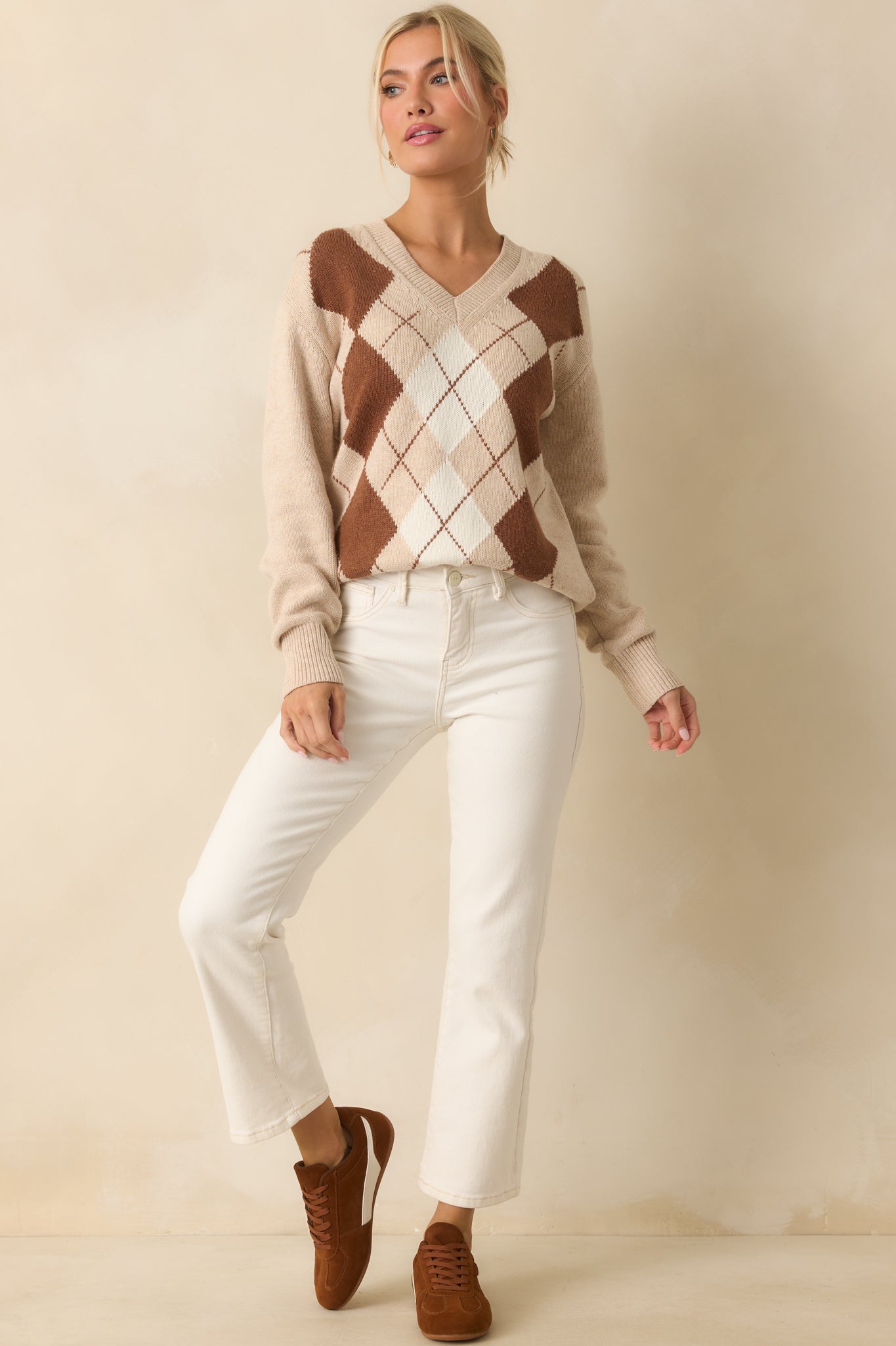 Relaxed fit beige sweater with long sleeves and classic brown and white argyle.