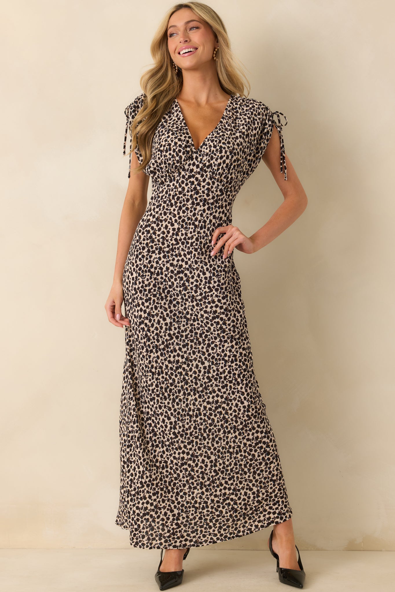 Black maxi dress with abstract floral design, cap sleeves with bows, and a floor-length skirt.