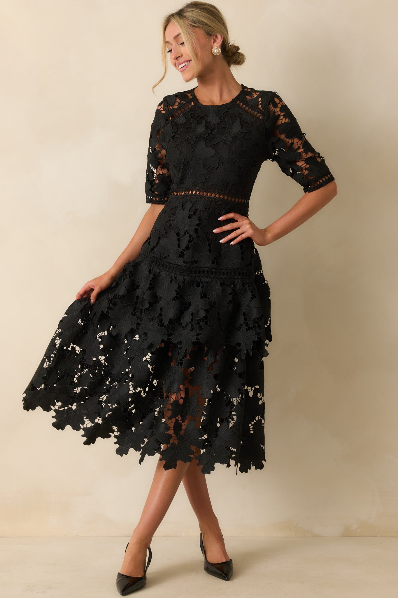 Black dress with a v-neckline, lace overlay, and tiered skirt design.