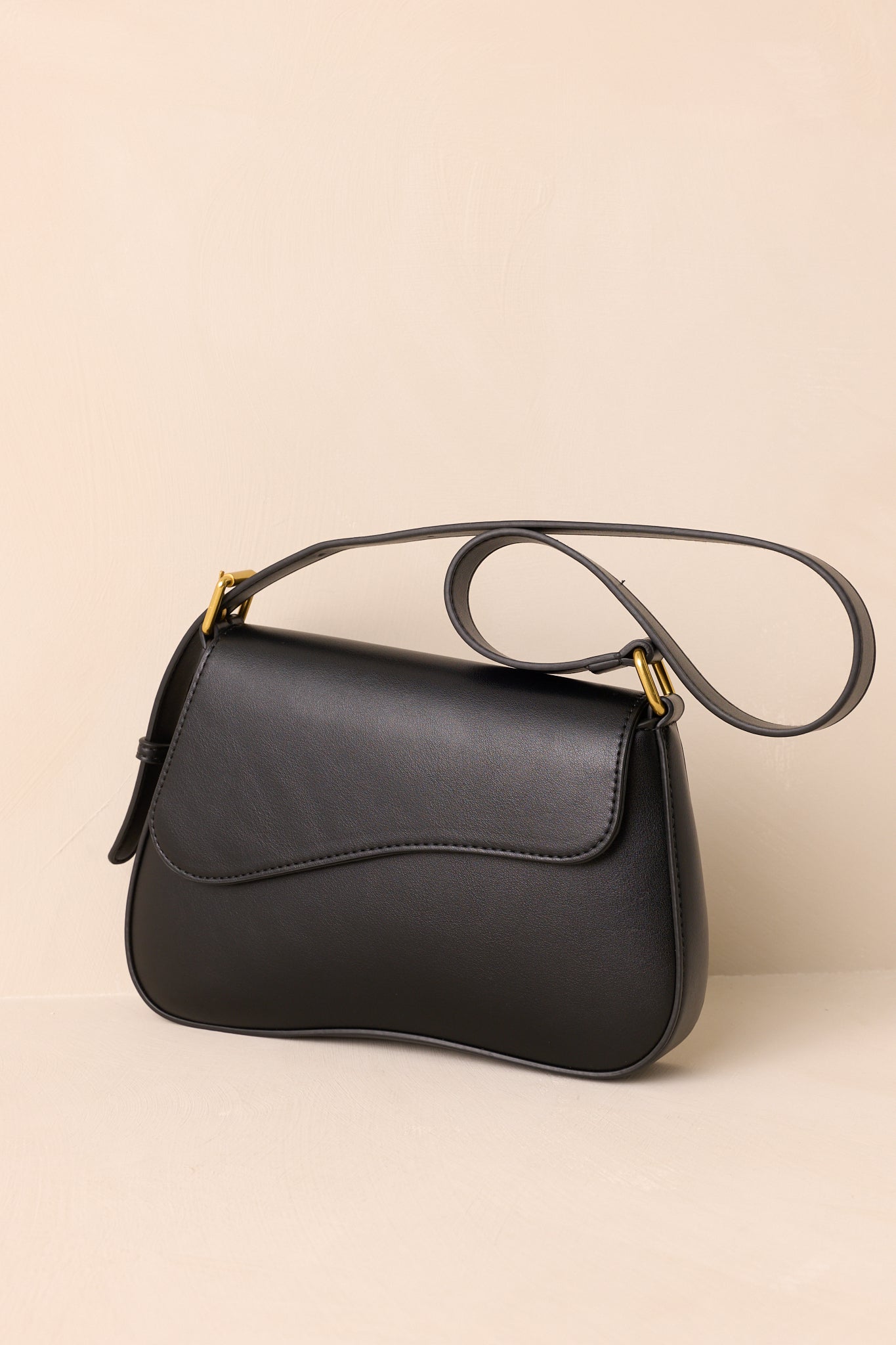 A cropped angled view focusing on the curved silhouette and gold-tone strap hardware.