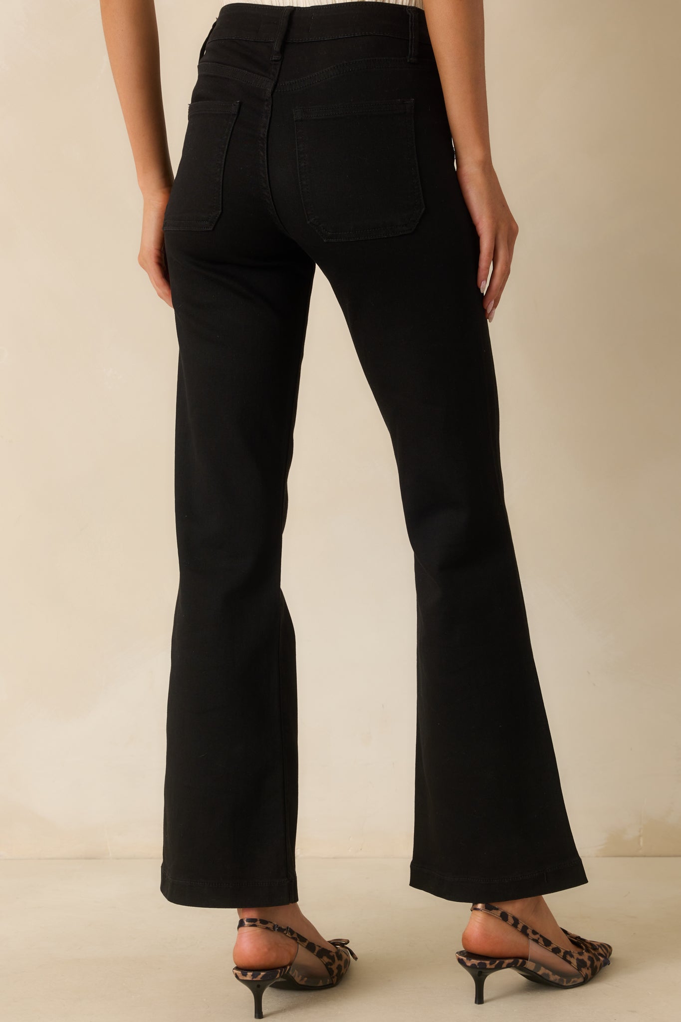 A back view of the black flare jeans with back patch pockets and flared silhouette.