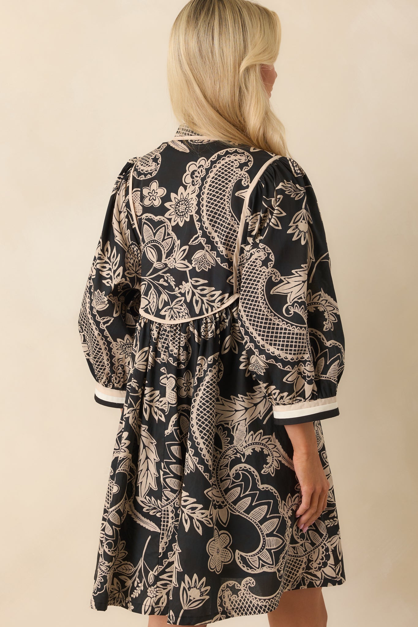 A back view of the mini dress showing the continuation of the floral print and cuffed sleeves.