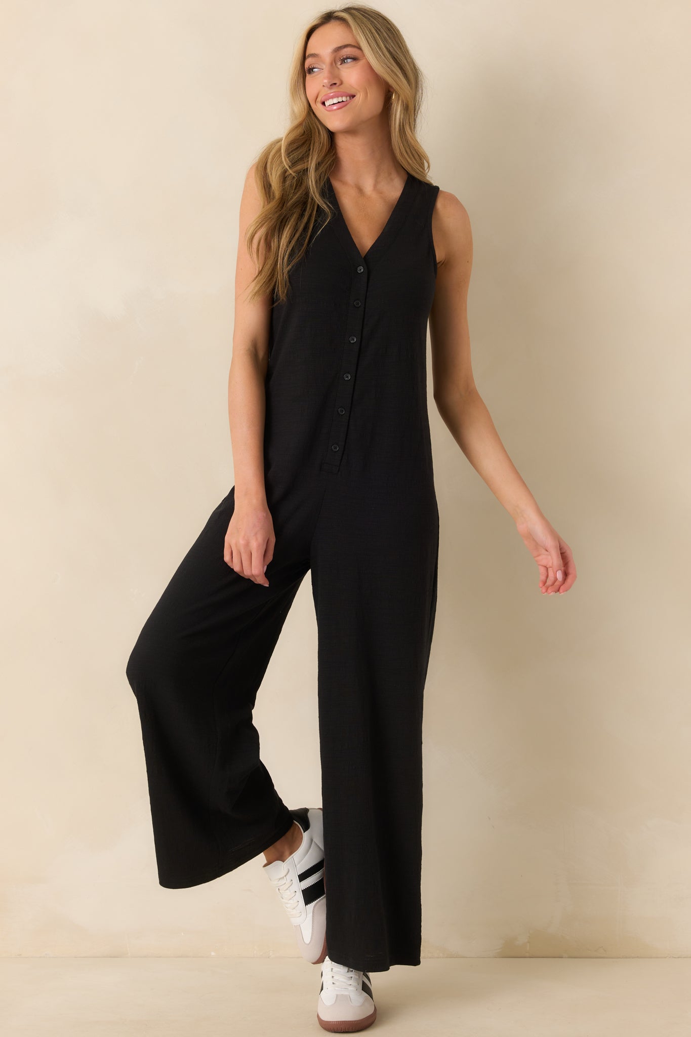 Full body front view of a black jumpsuit with a v-neckline and wide leg design.