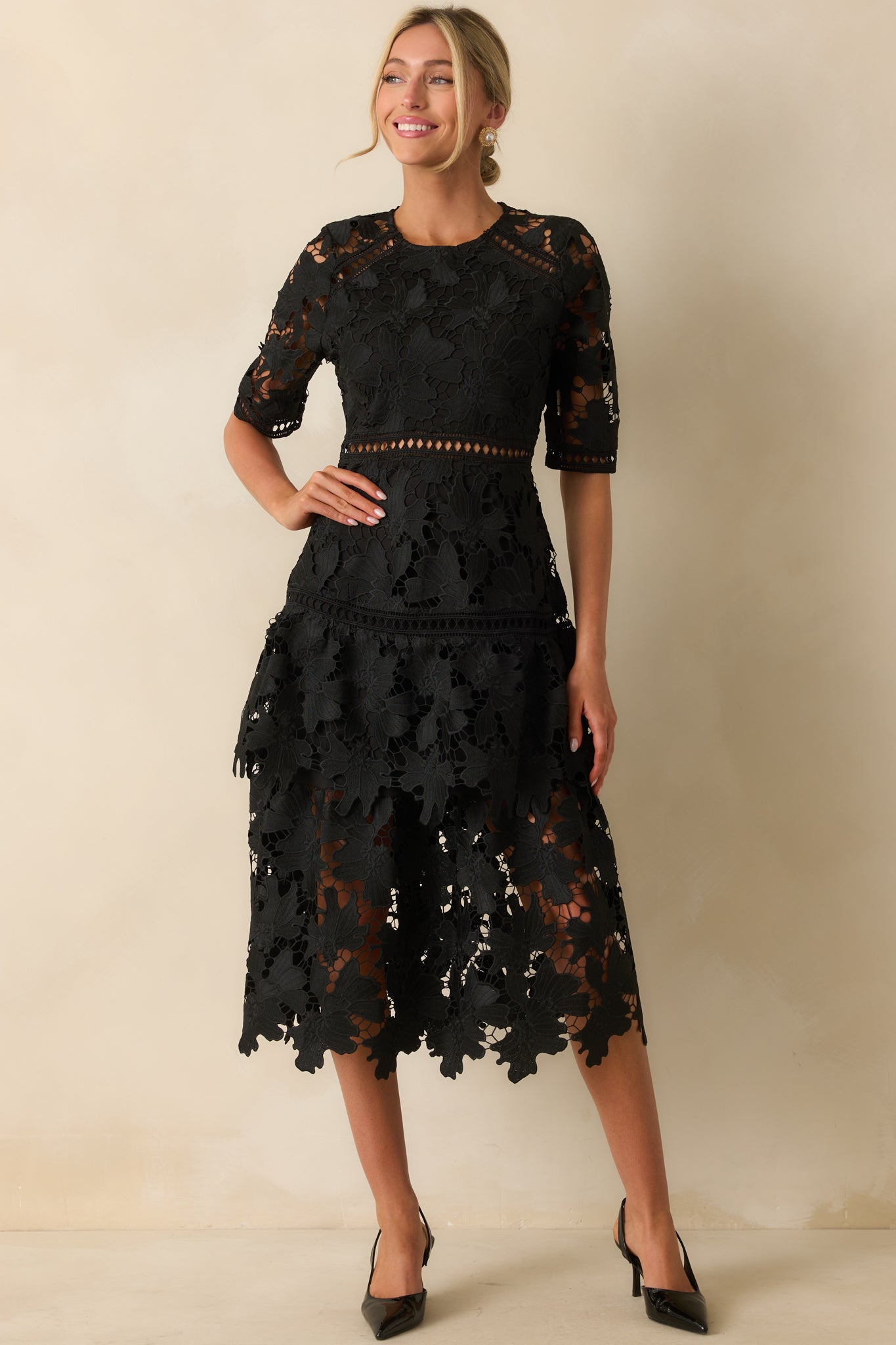 Black lace dress with a fitted bodice and flowing tiered skirt silhouette.