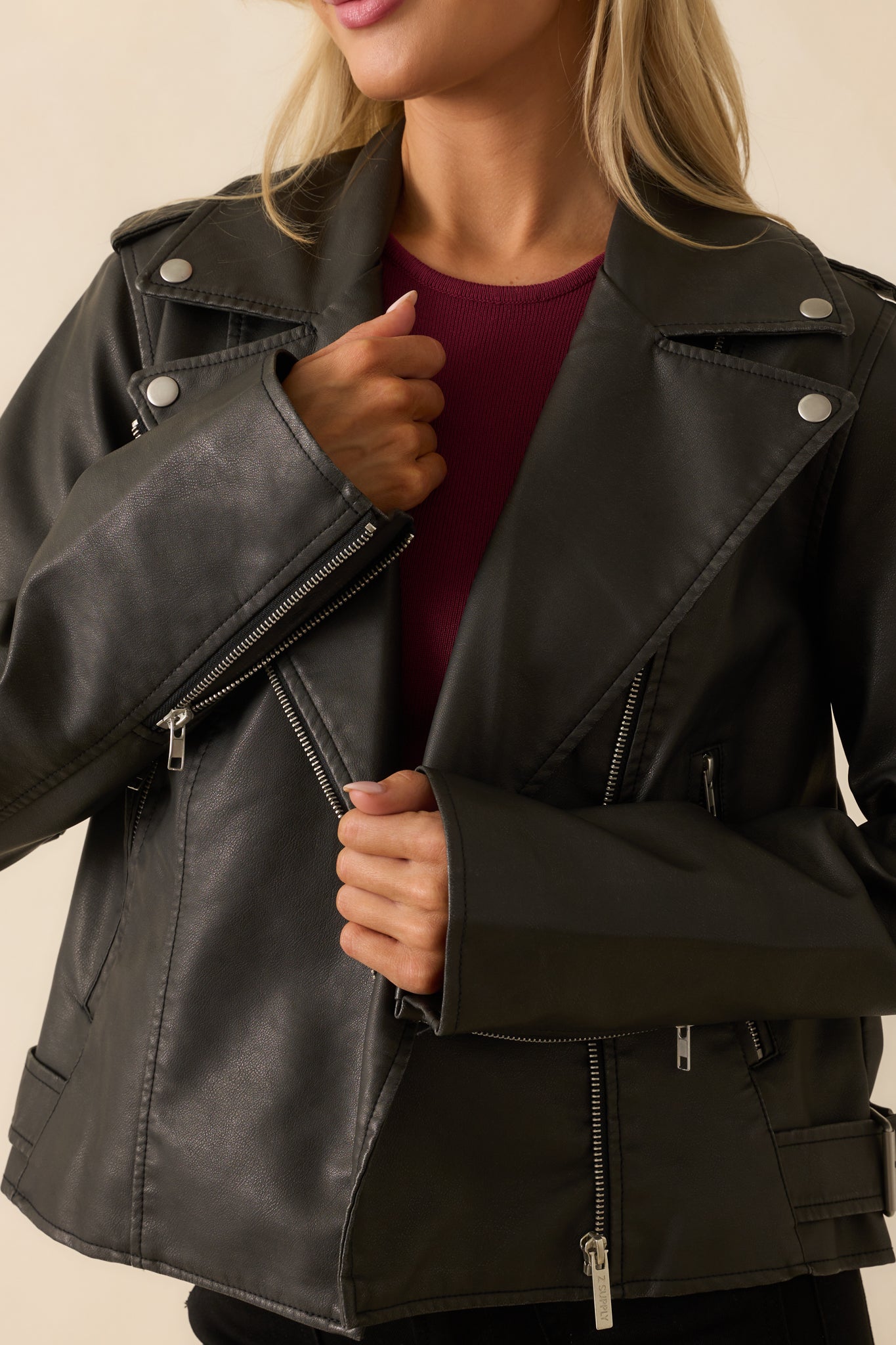 Close-up of the collar and top zipper pull on the black moto jacket.
