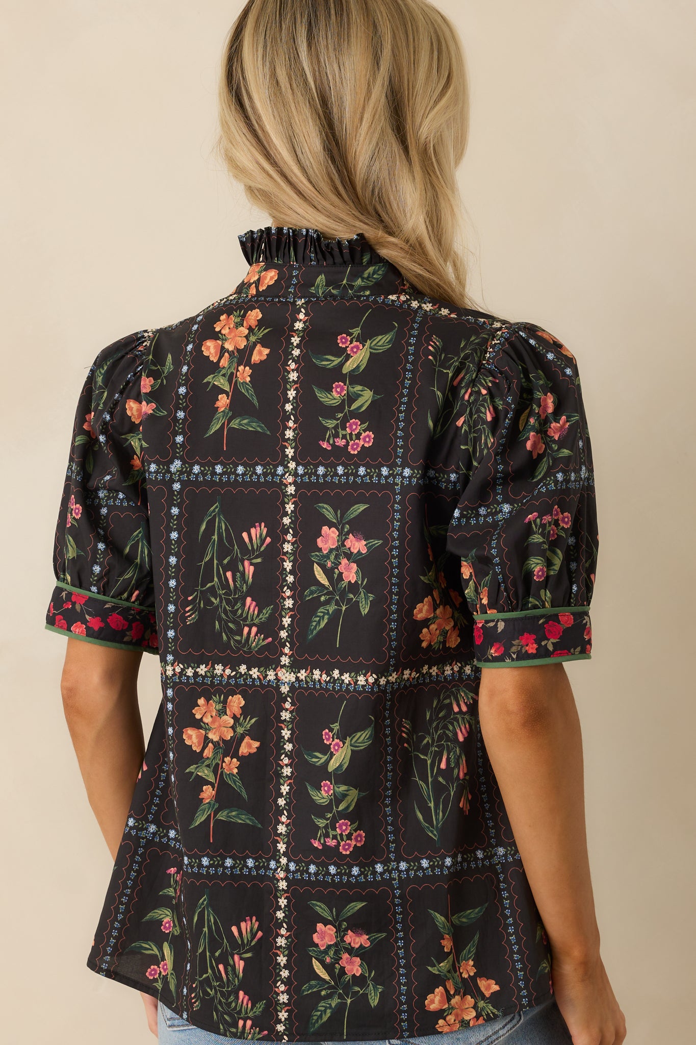 A back view of the black top with a multicolor floral patchwork design and a loose, relaxed fit.