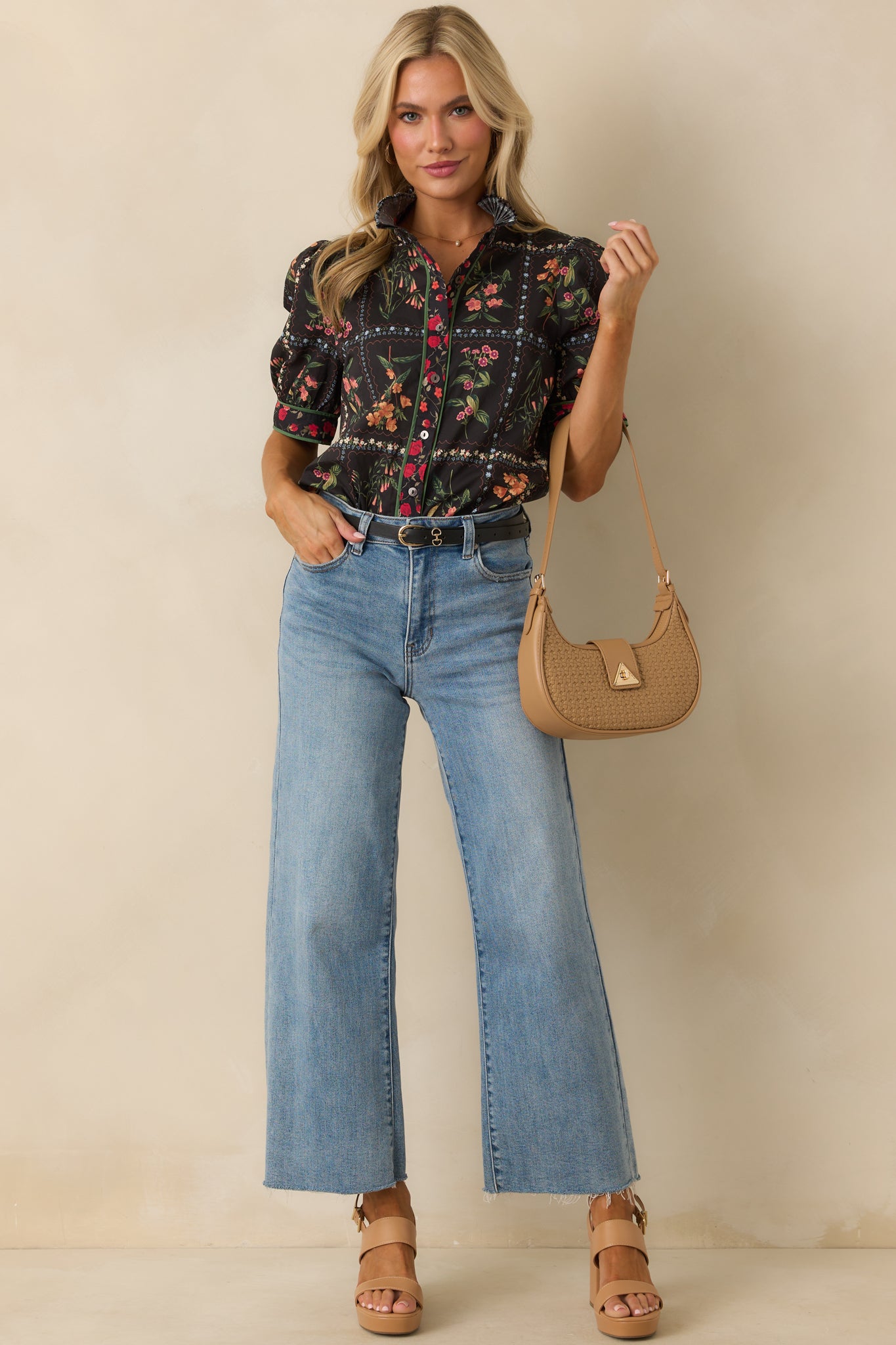 A full body view of the black patchwork floral print top styled with a pleated ruffle collar and green edging.