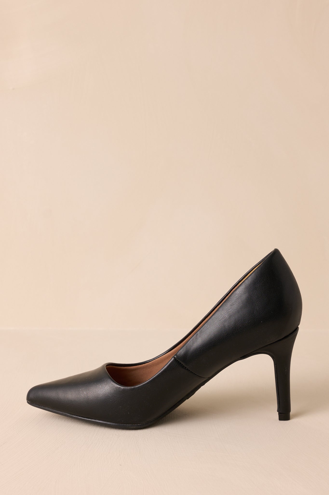 Side view of the black pumps showing the pointed toe and elegant shape.