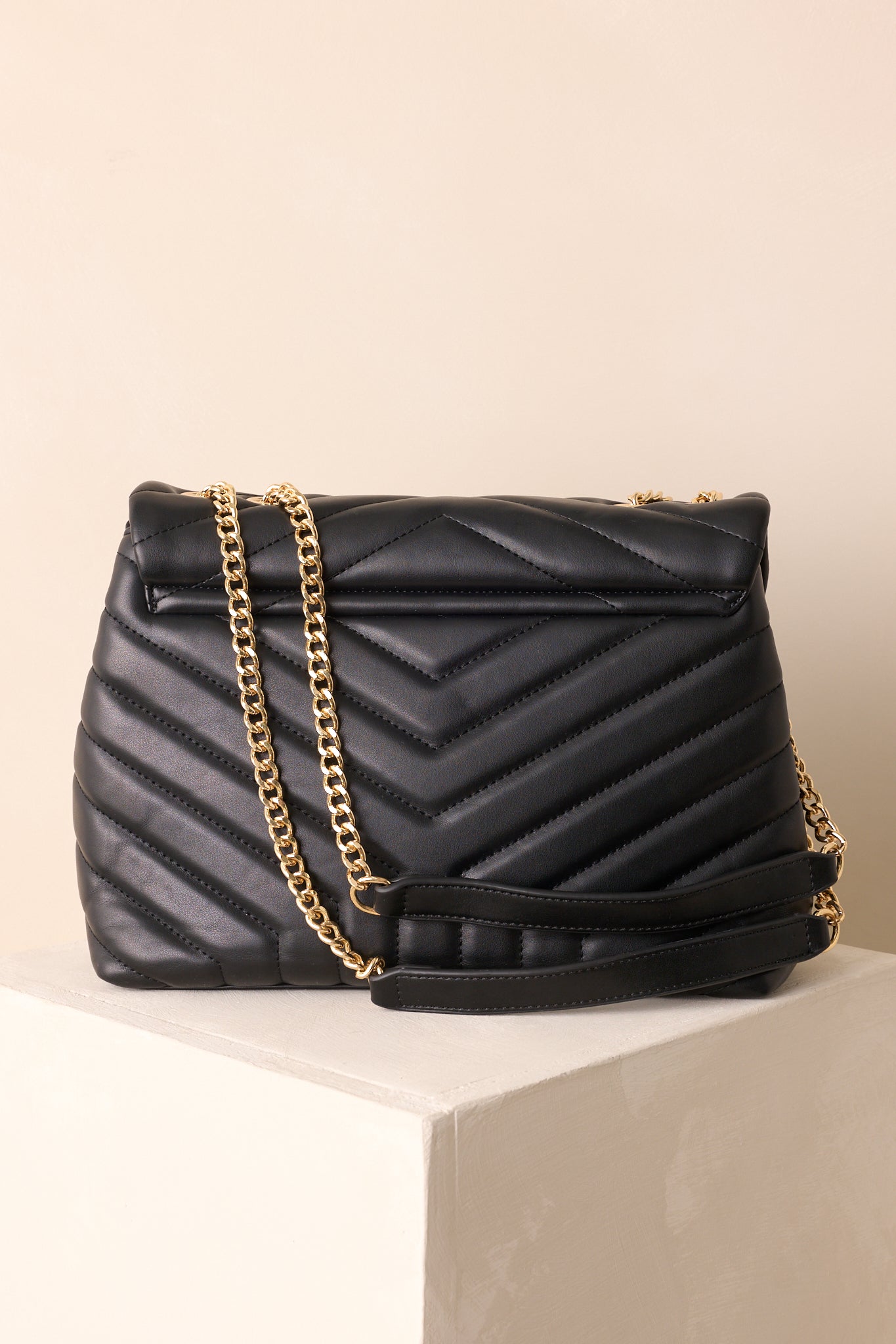 Rear view of black quilted handbag showing smooth panel and structured shape.