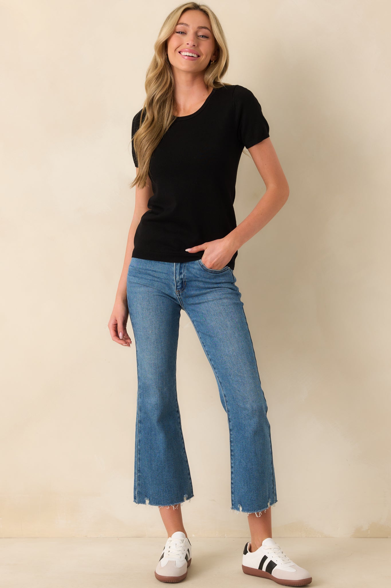 A full length shot emphasizing the casual fit and clean lines of the black sweater top.