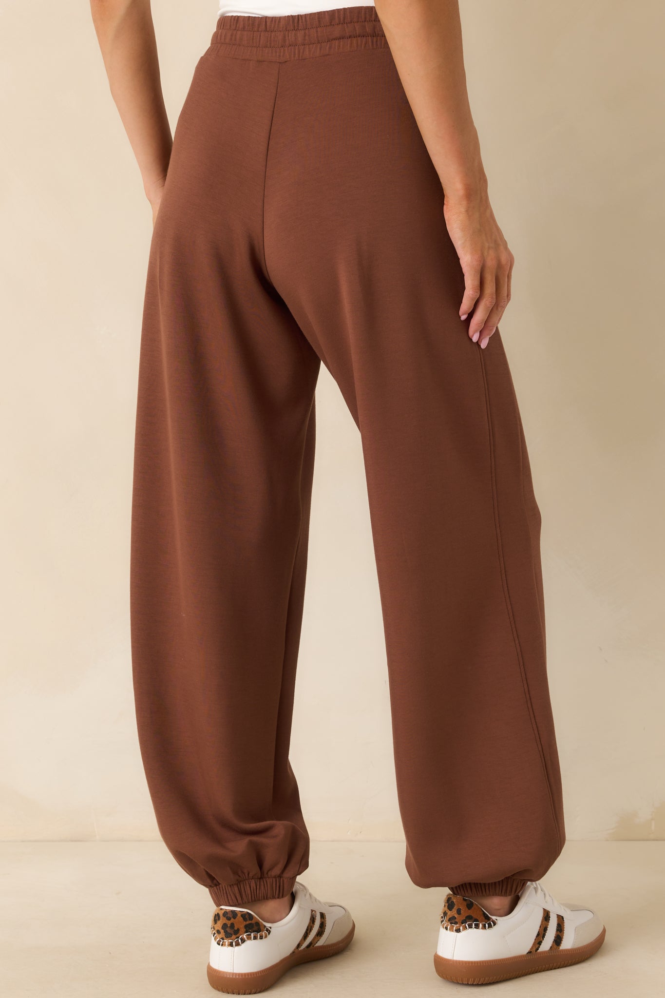 A view from behind of the brown joggers showing the elastic waistband and cuffed ankles.