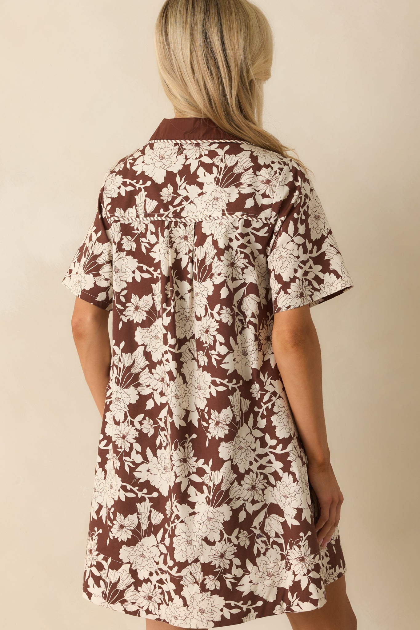 A view from behind of the brown mini dress showing the structured back and short sleeves.