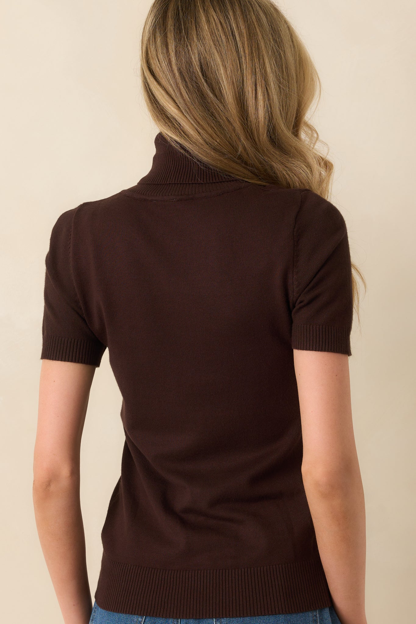 A view from behind showing the overall structure, ribbing, and rolled neckline of the brown sweater.