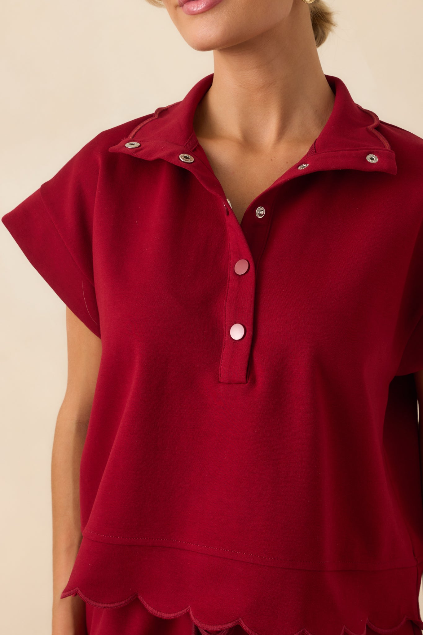 A detailed close-up of the scalloped hem embroidery and textured stitching along the sleeve and bottom edge.