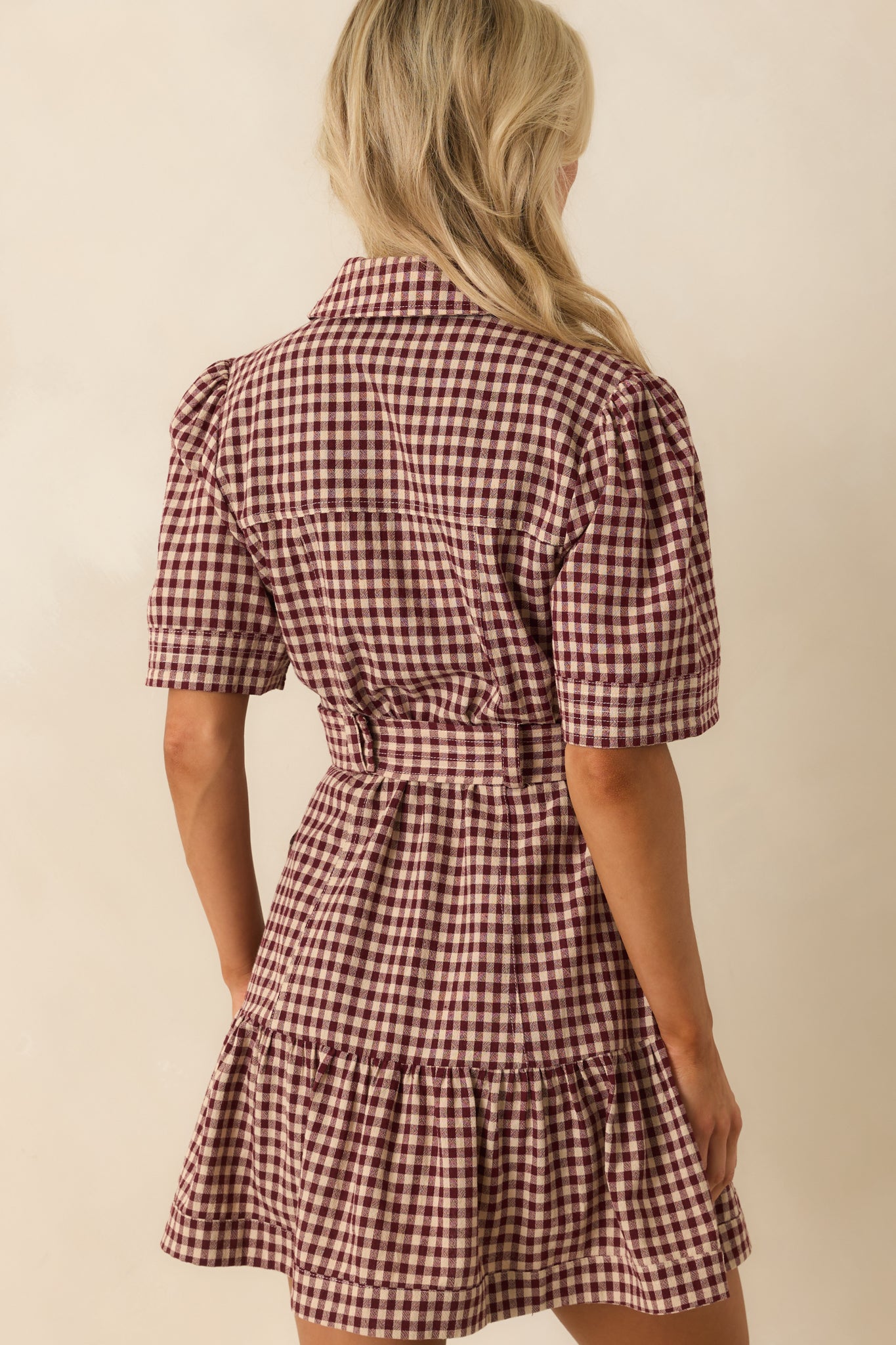 A view from behind of the gingham dress, showing the belt placement and continuation of the tiered skirt.
