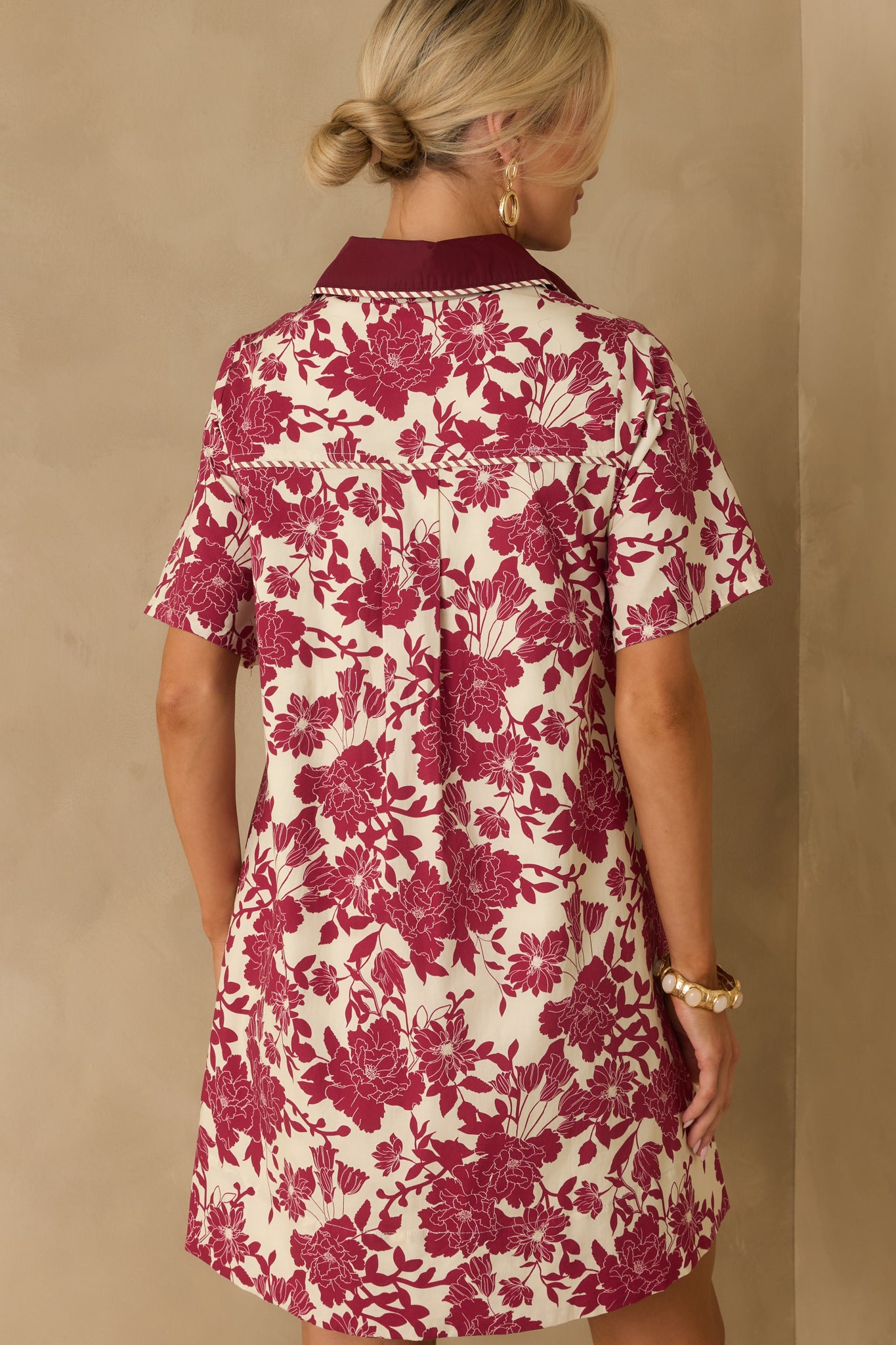 Rear view of burgundy mini dress with ivory floral print and striped trim accents.