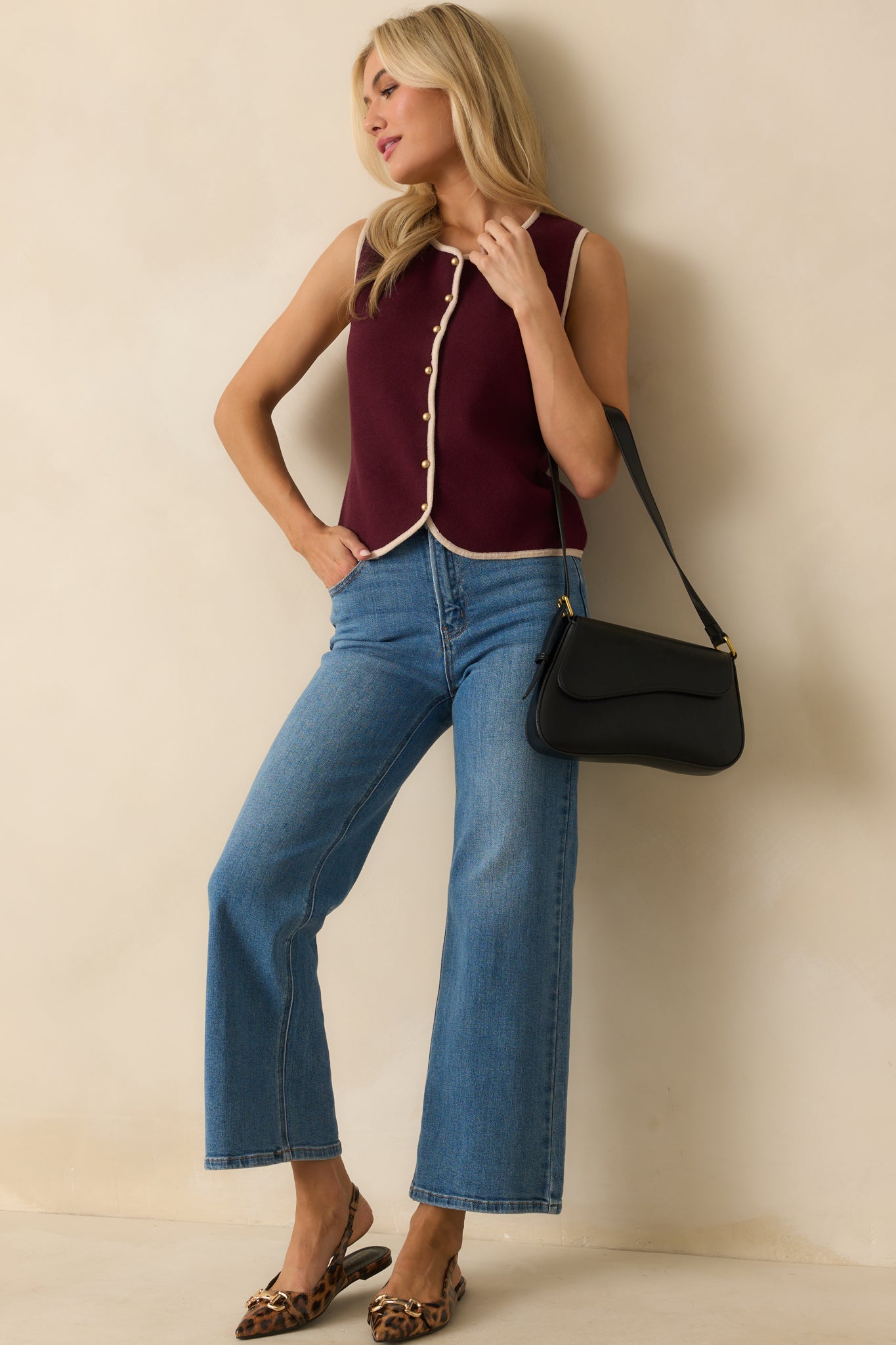 Burgundy sweater vest with ivory trim and a button front closure.