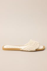 Side view of  these ivory flats that feature a square toe, a slip-on design, and a strap across the top of the foot with a knitted texture. 