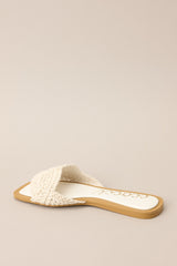 Back angled view of  these ivory flats that feature a square toe, a slip-on design, and a strap across the top of the foot with a knitted texture. 
