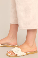 These ivory flats feature a square toe, a slip-on design, and a strap across the top of the foot with a knitted texture. 