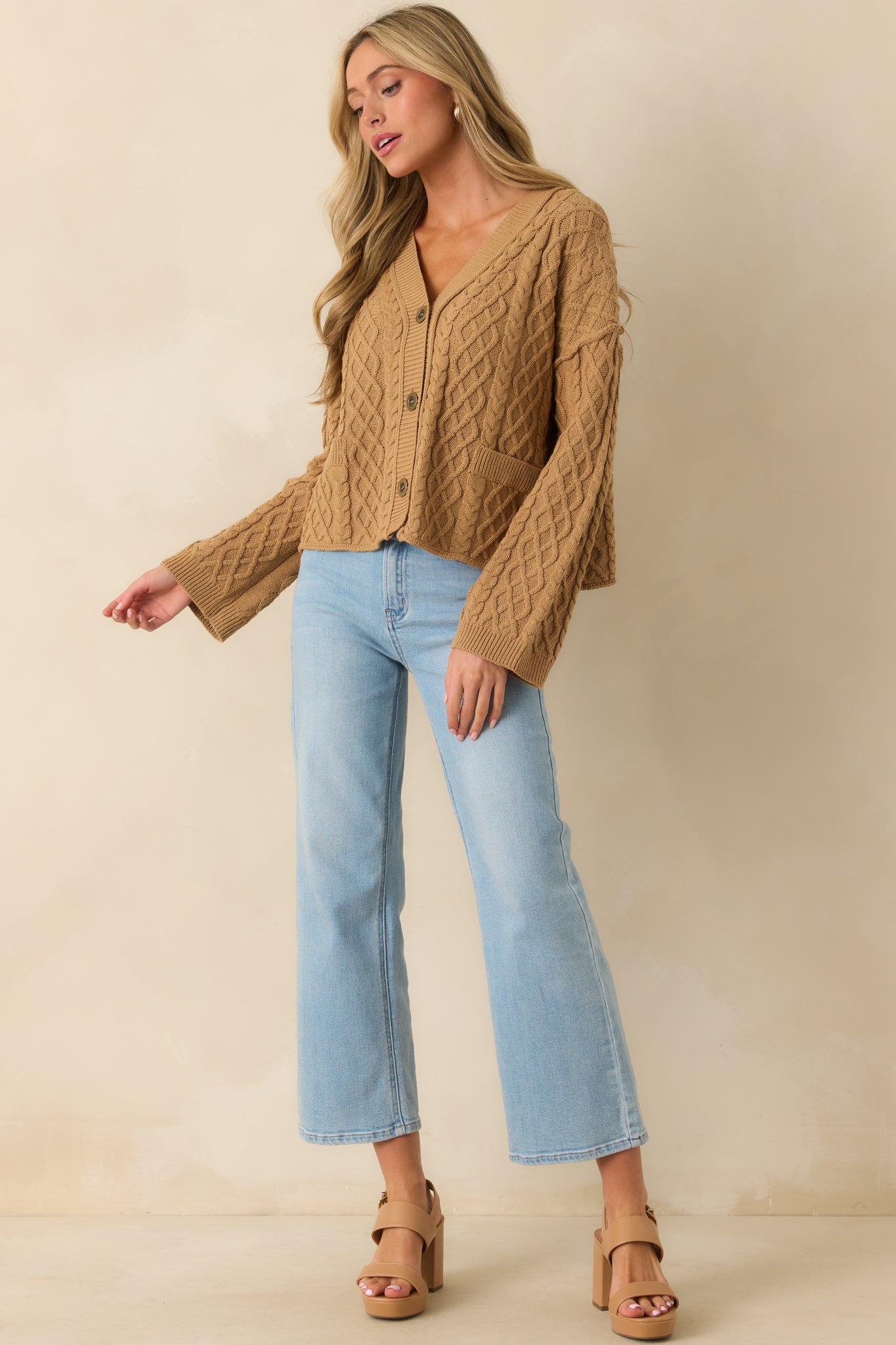 Full front view of the camel brown cable knit cardigan with v-neckline and button front closure.