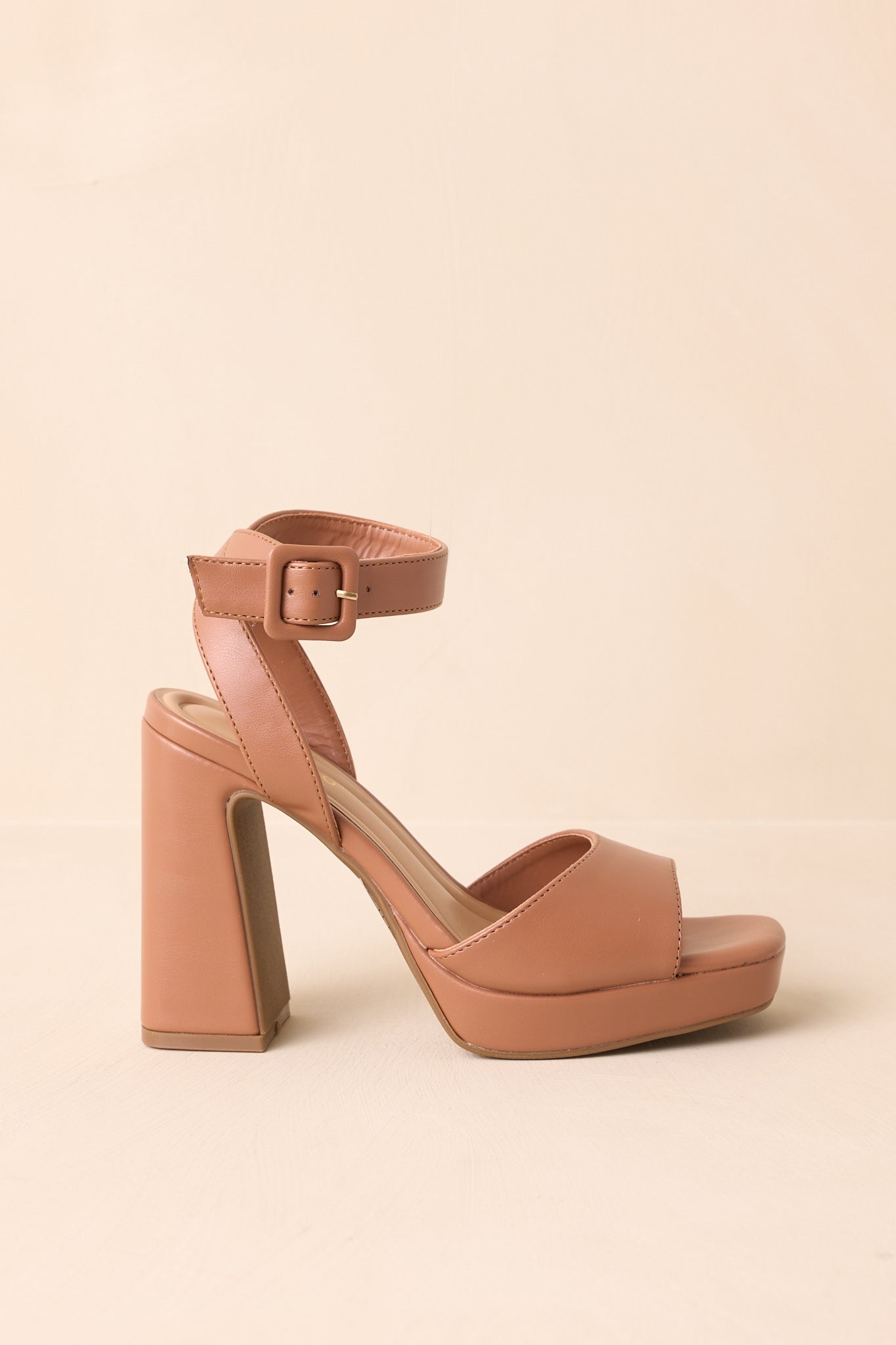 Cropped image highlighting the side of the brown heels, displaying the block heel and faux leather material.