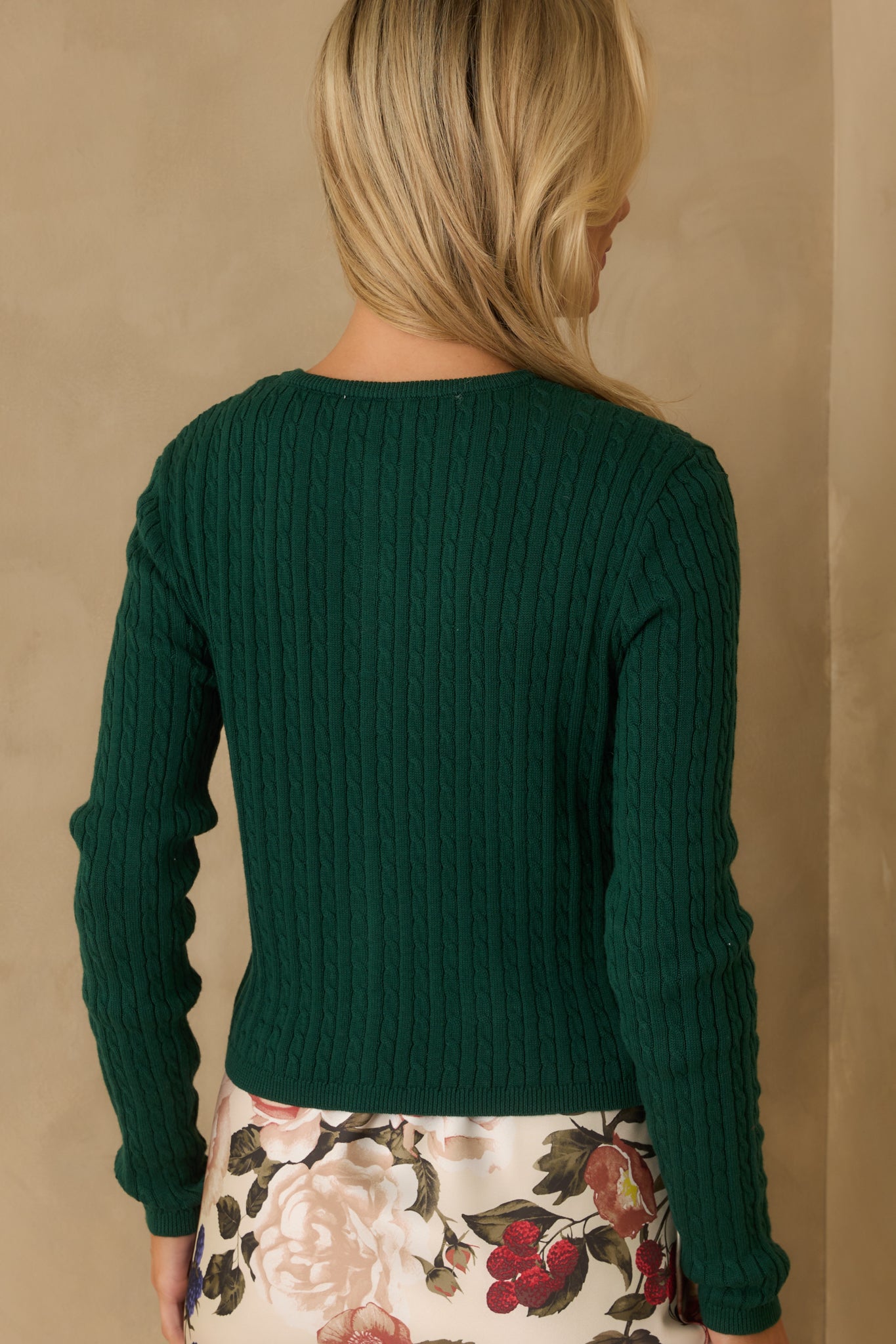 A view from behind of the cardigan, displaying the back panel’s cable knit design and the cardigan’s overall fit.