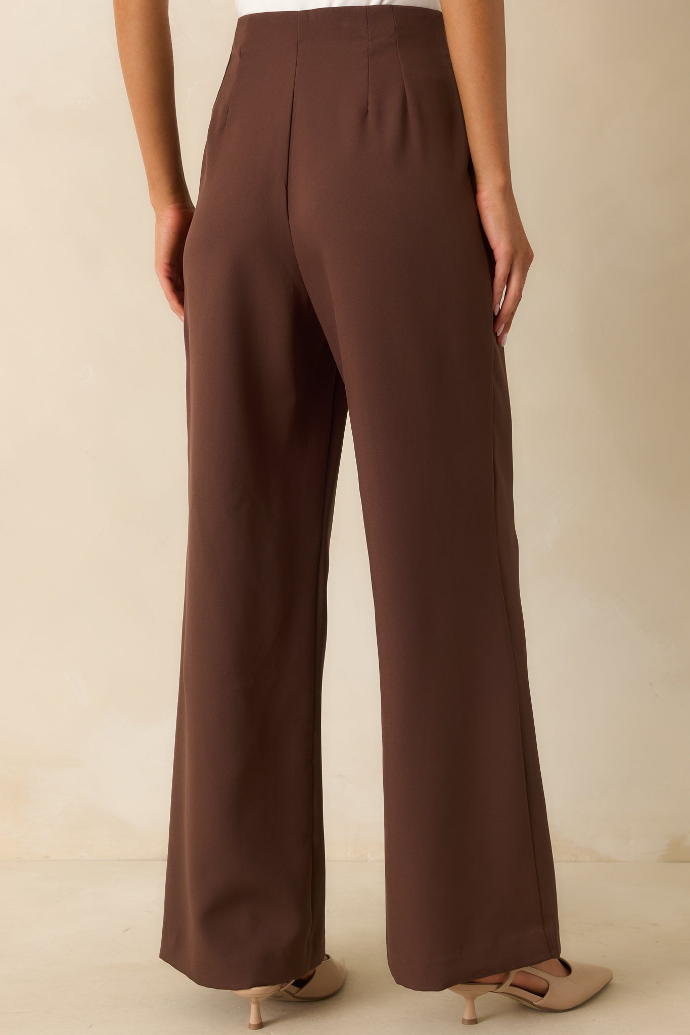 Rear view of the chocolate brown trousers with a smooth waistband and tailored drape.