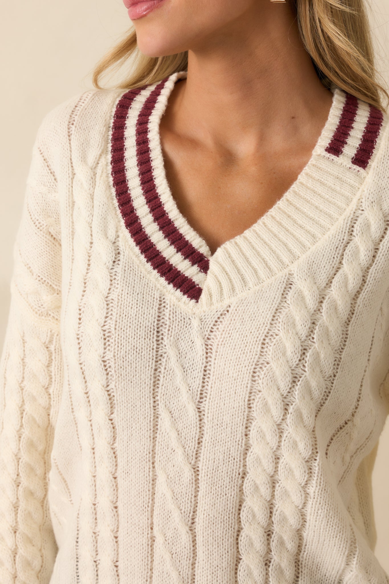 Close-up of the burgundy trim and ribbed hems on the ivory sweater.