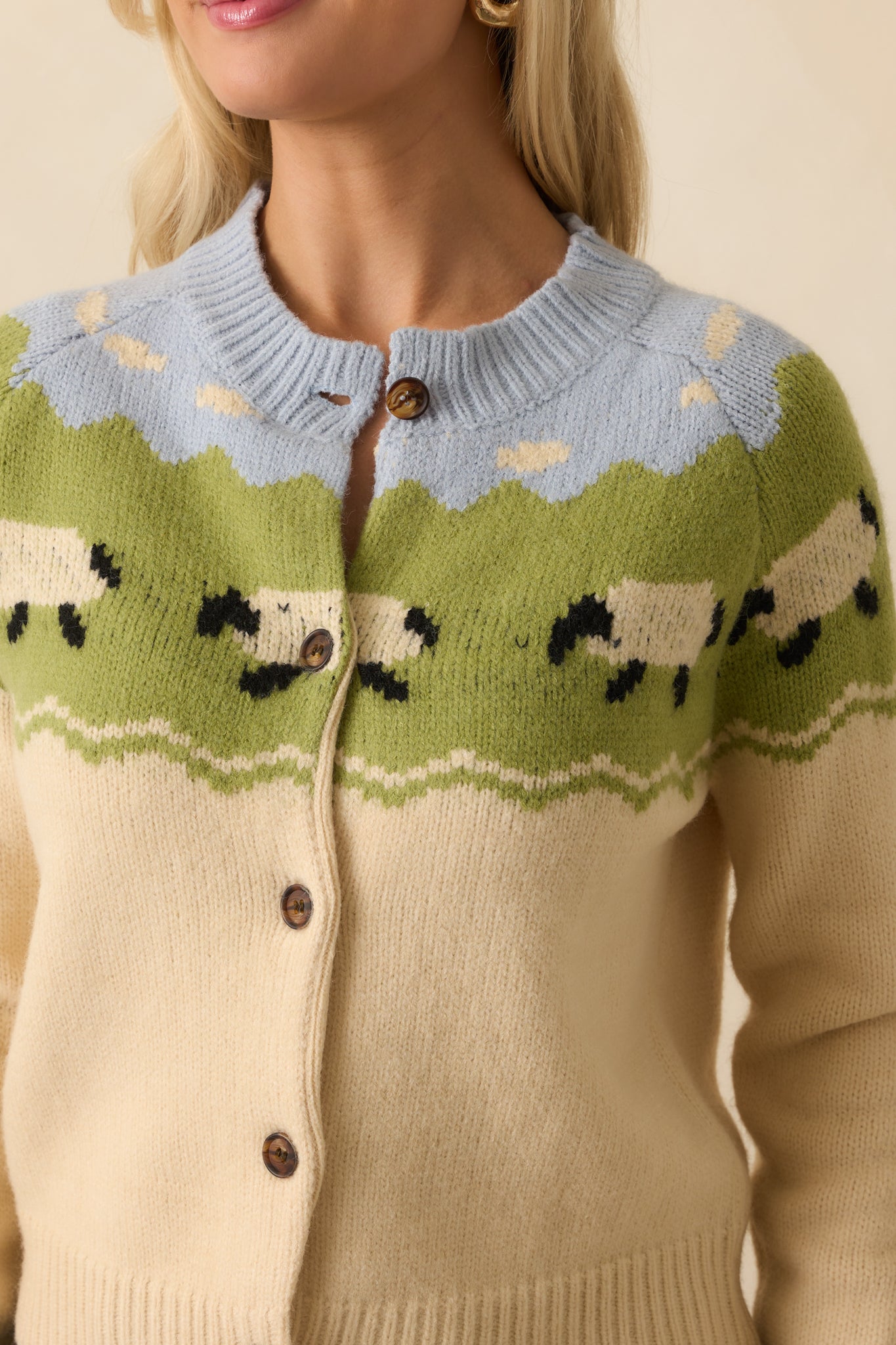 Close-up detail of ecru cardigan’s knit fabric and multicolor sheep and cloud yoke motif.