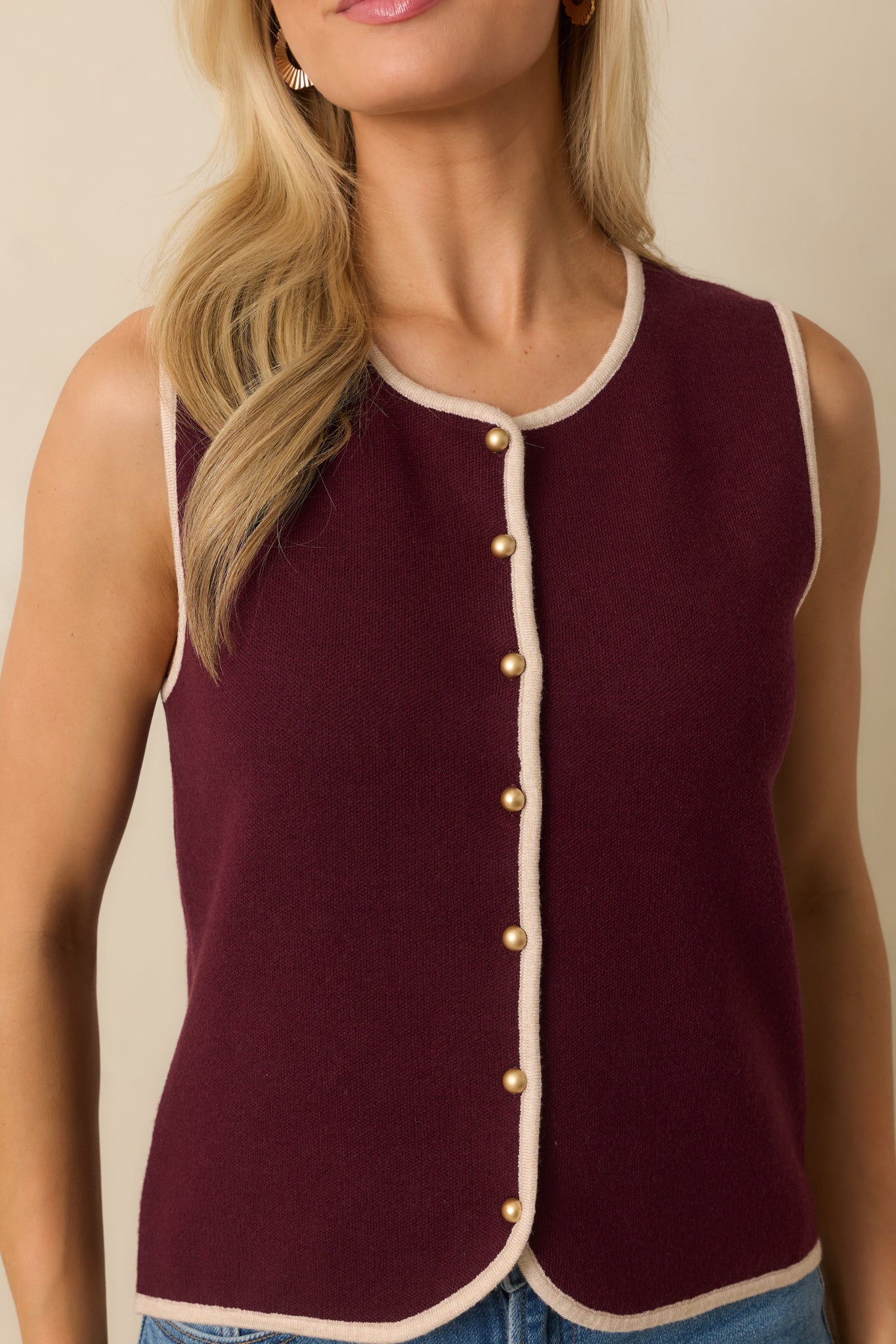 Close-up of the gold dome buttons and ivory trim on the burgundy sweater vest.