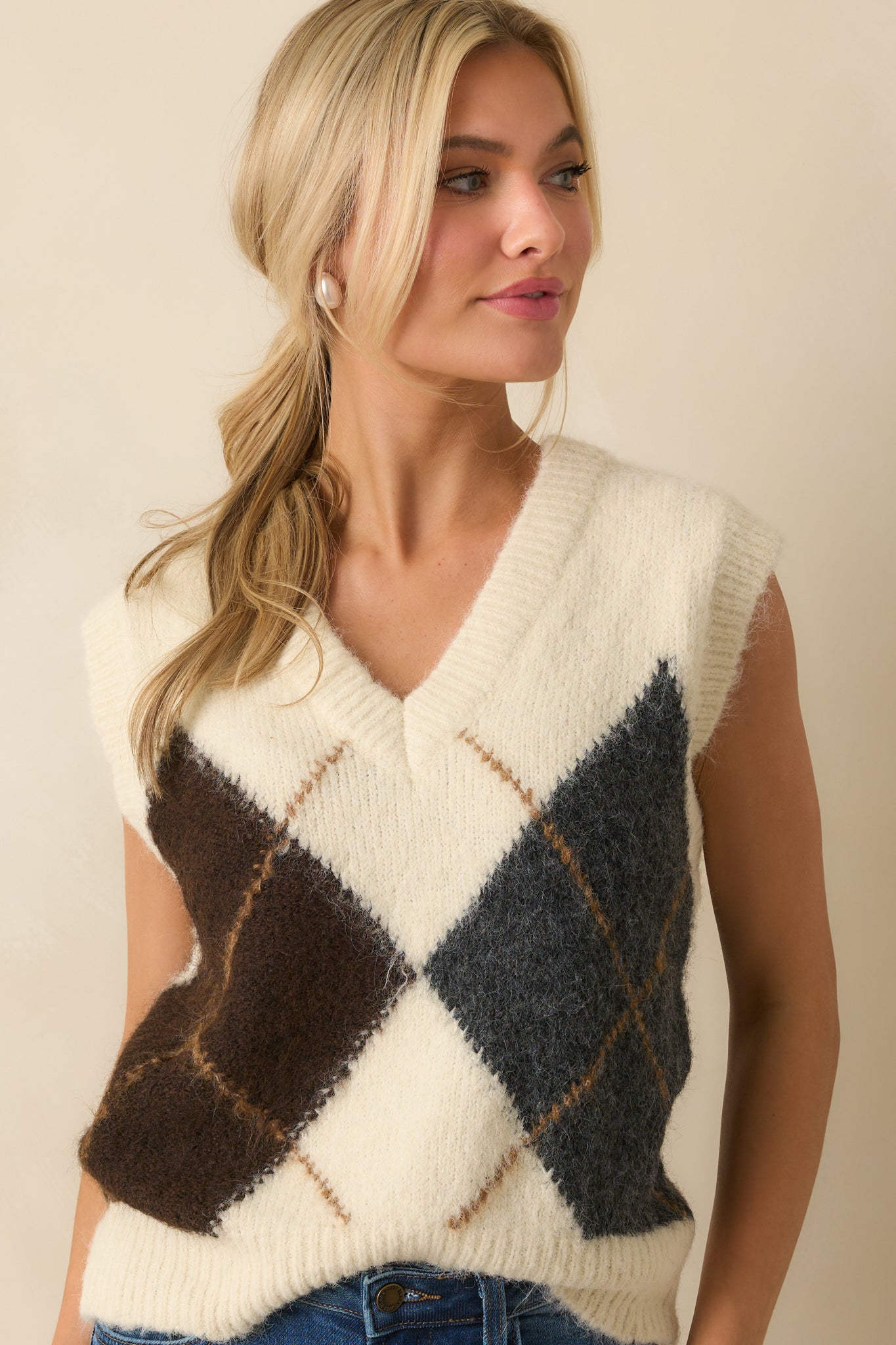 Close view of the v-neckline and large argyle pattern on the ivory vest.