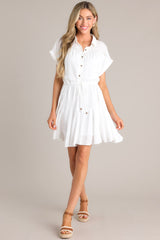 Front view of this white dress features a collared neckline, semi-transparent lace, a half button front, a self-tie waist feature, a lightweight fabric, and folded short sleeves.