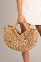 This tan and gold bag features a woven design with gold throughout and a wooden handle.