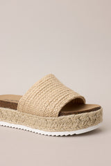 Close up side view of these natural sandals with rounded toe, slip-on design, strap over foot, espadrille detailing, textured sole.