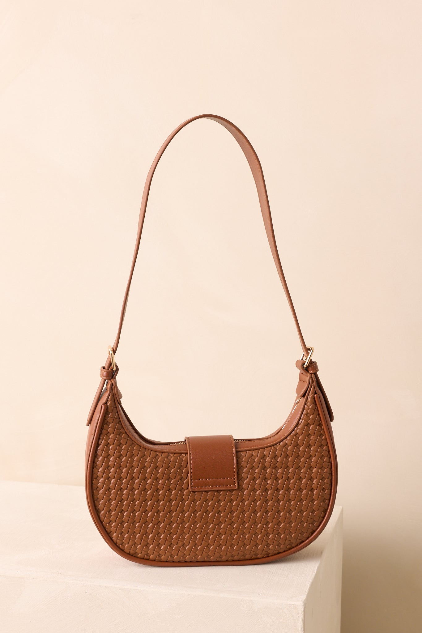 Rear view of cognac brown shoulder bag with smooth panel and flat adjustable strap.