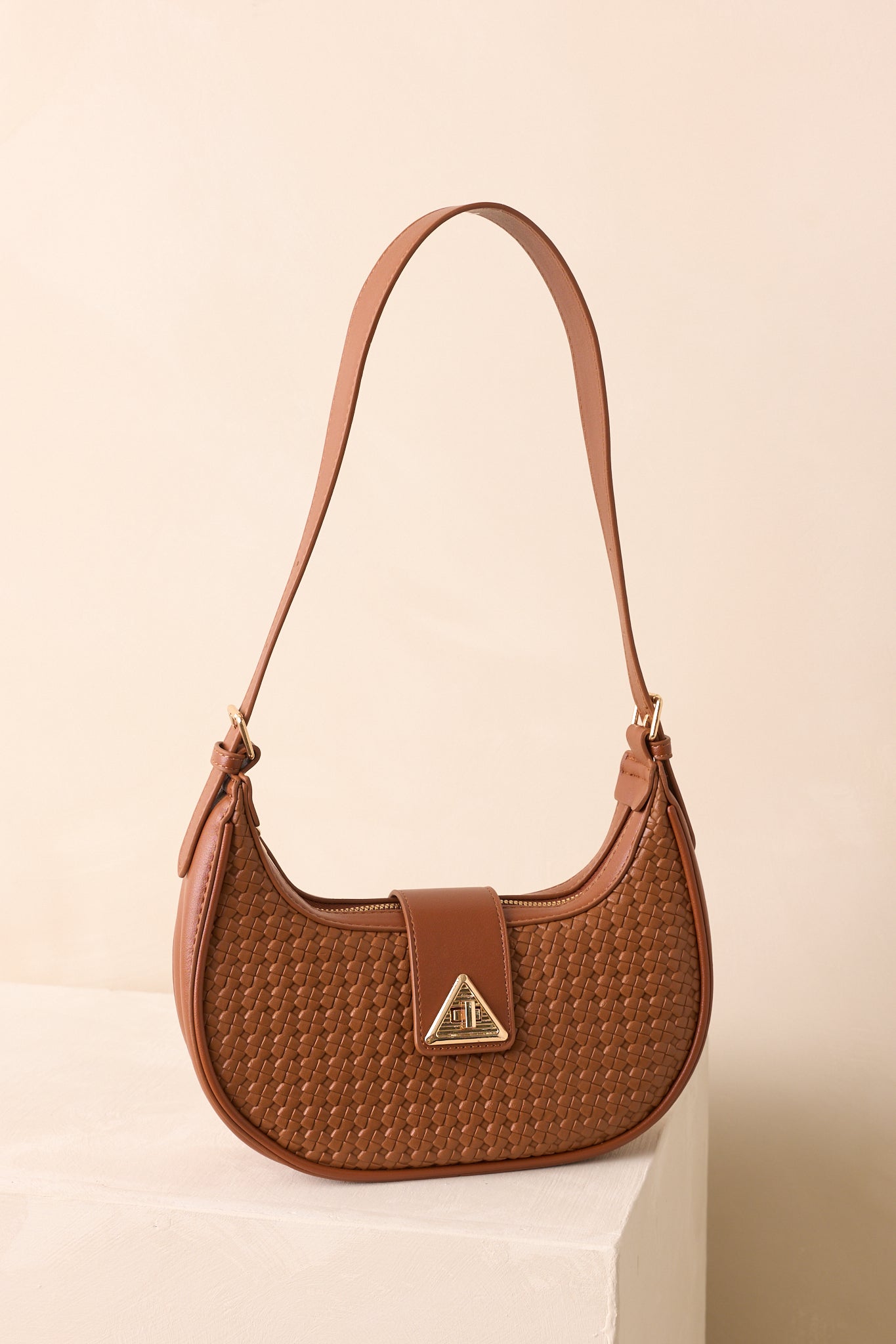 Cognac brown shoulder bag highlighting structured base and gold zipper closure.