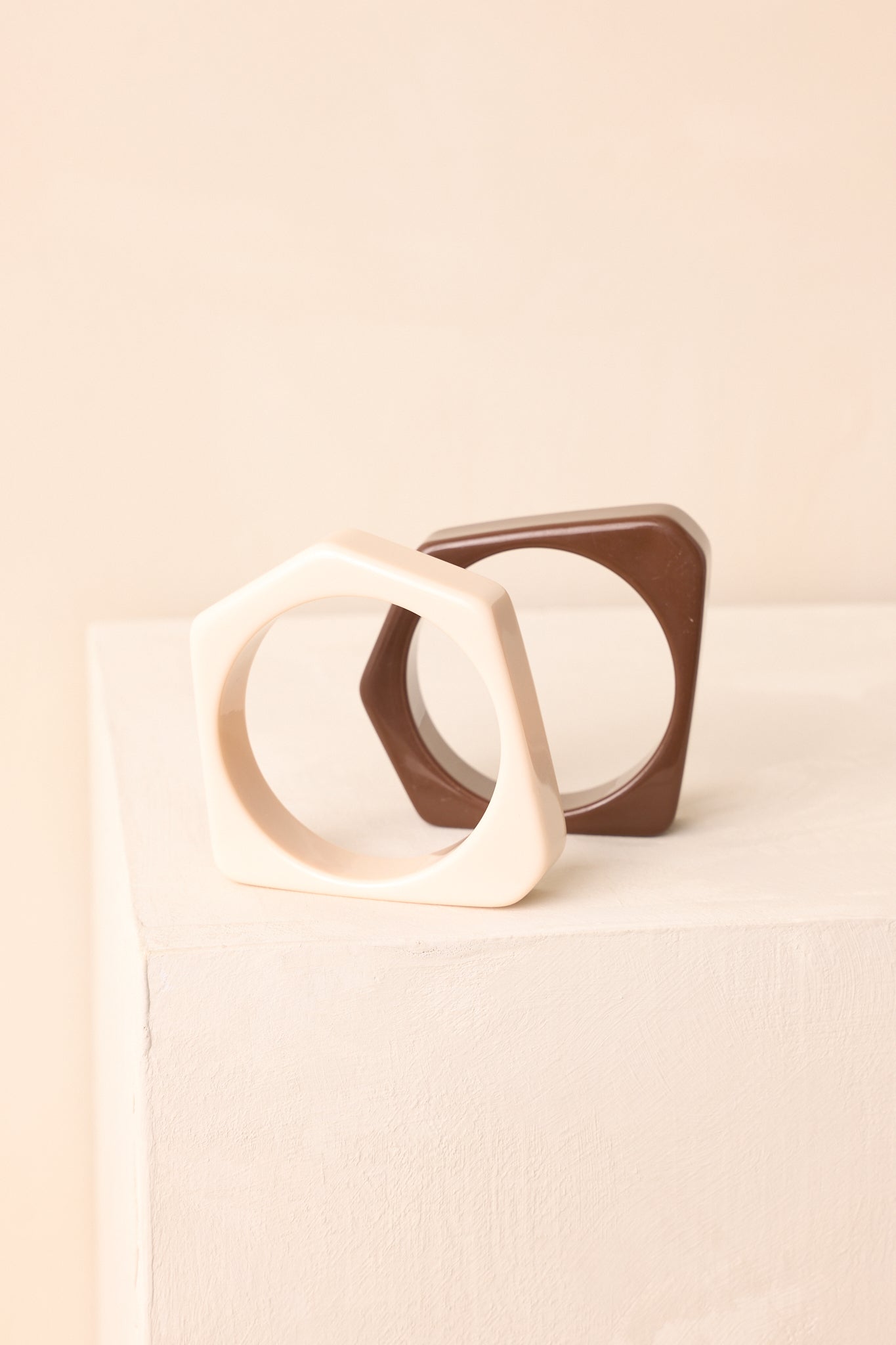 A close-up detailed image revealing the glossy finish and sharp square-edge silhouette of the cream and brown bangle set.