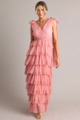 Full body view of this pink dress featuring a flattering v-neckline, graceful fabric trailing from the shoulders, a chic self-tie waist belt, and multiple tiers and layers of ethereal tulle for a whimsical touch.