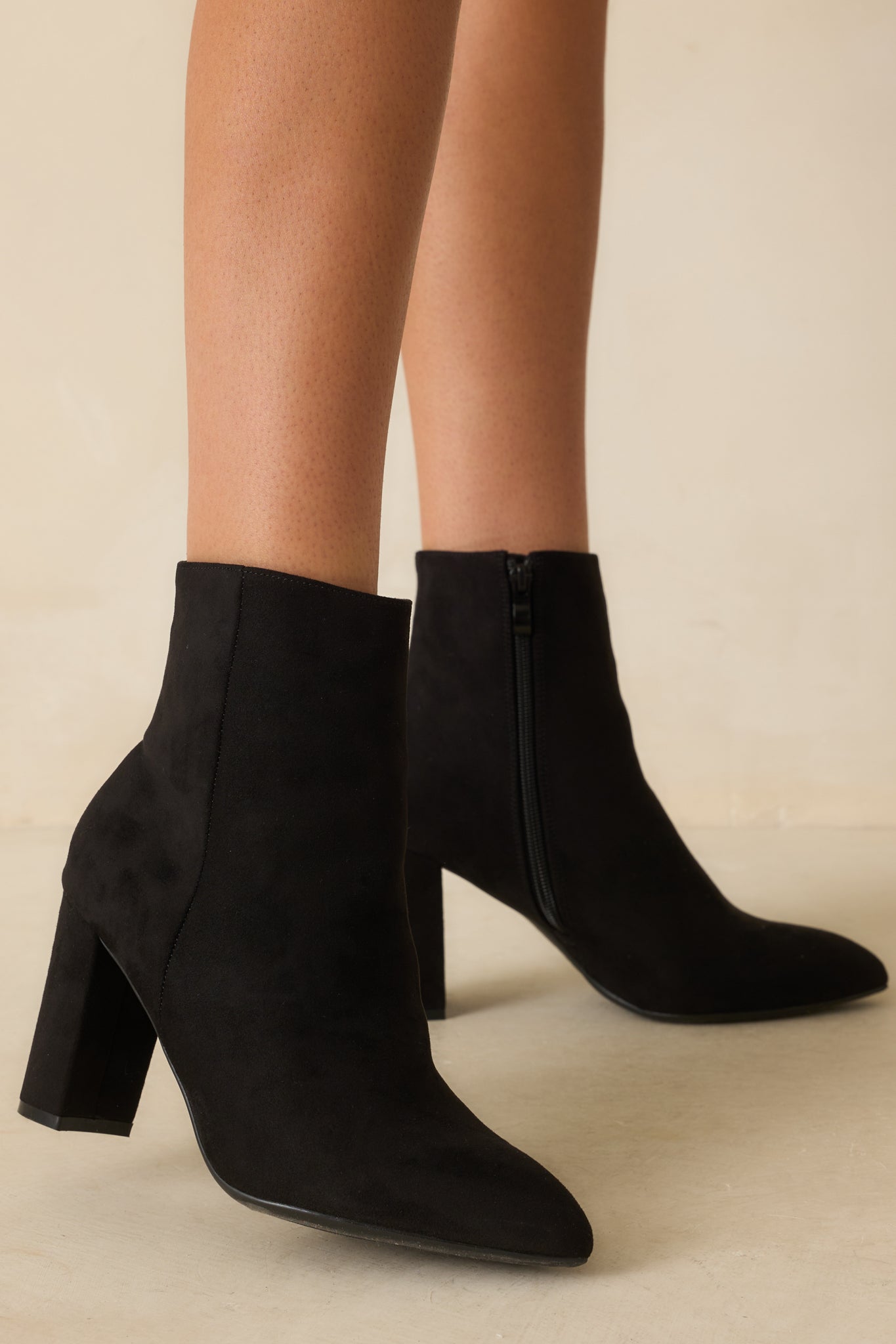A cropped side view of the black boots highlighting the pointed toe and smooth faux suede material.