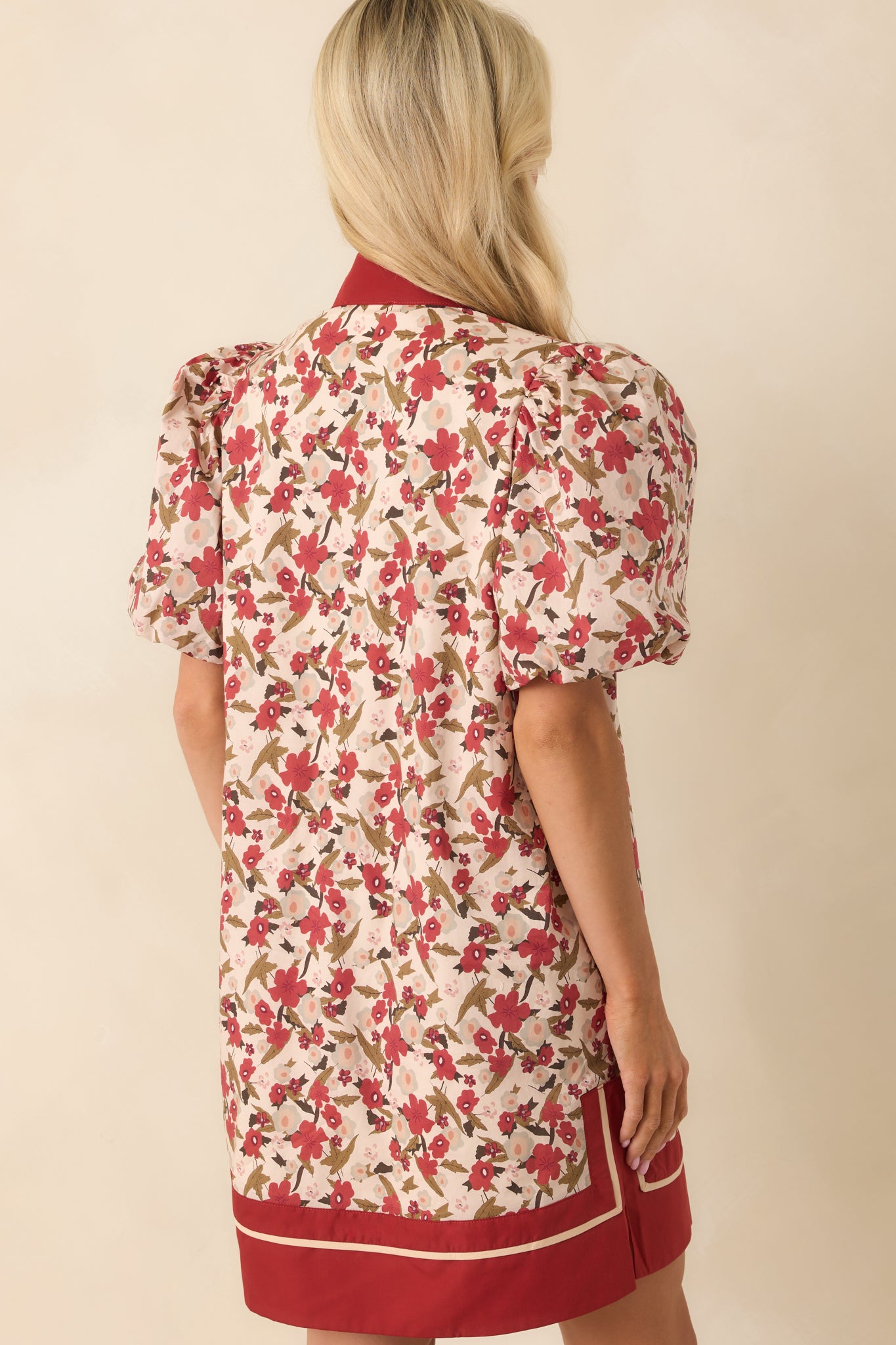 A back view of the dark rust mini dress showing the continuation of the floral print and puff sleeve silhouette.
