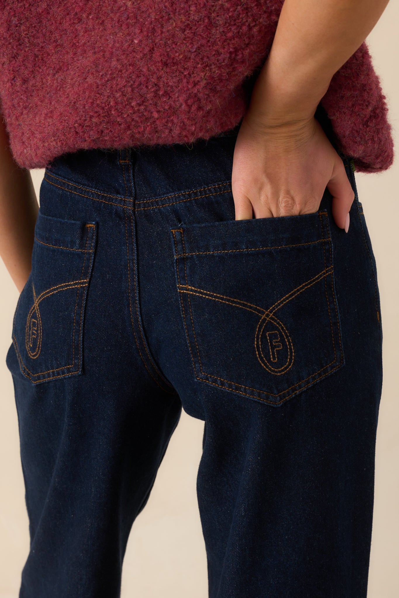 Close-up of the dark wash denim fabric showing stitching details, waistband, and back pocket detailing.