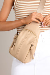 This tan sling bag showcases elegant gold hardware and a practical crossbody design, complete with an adjustable strap for customizable wear. Additionally, it offers functional pockets to keep your essentials organized and accessible.