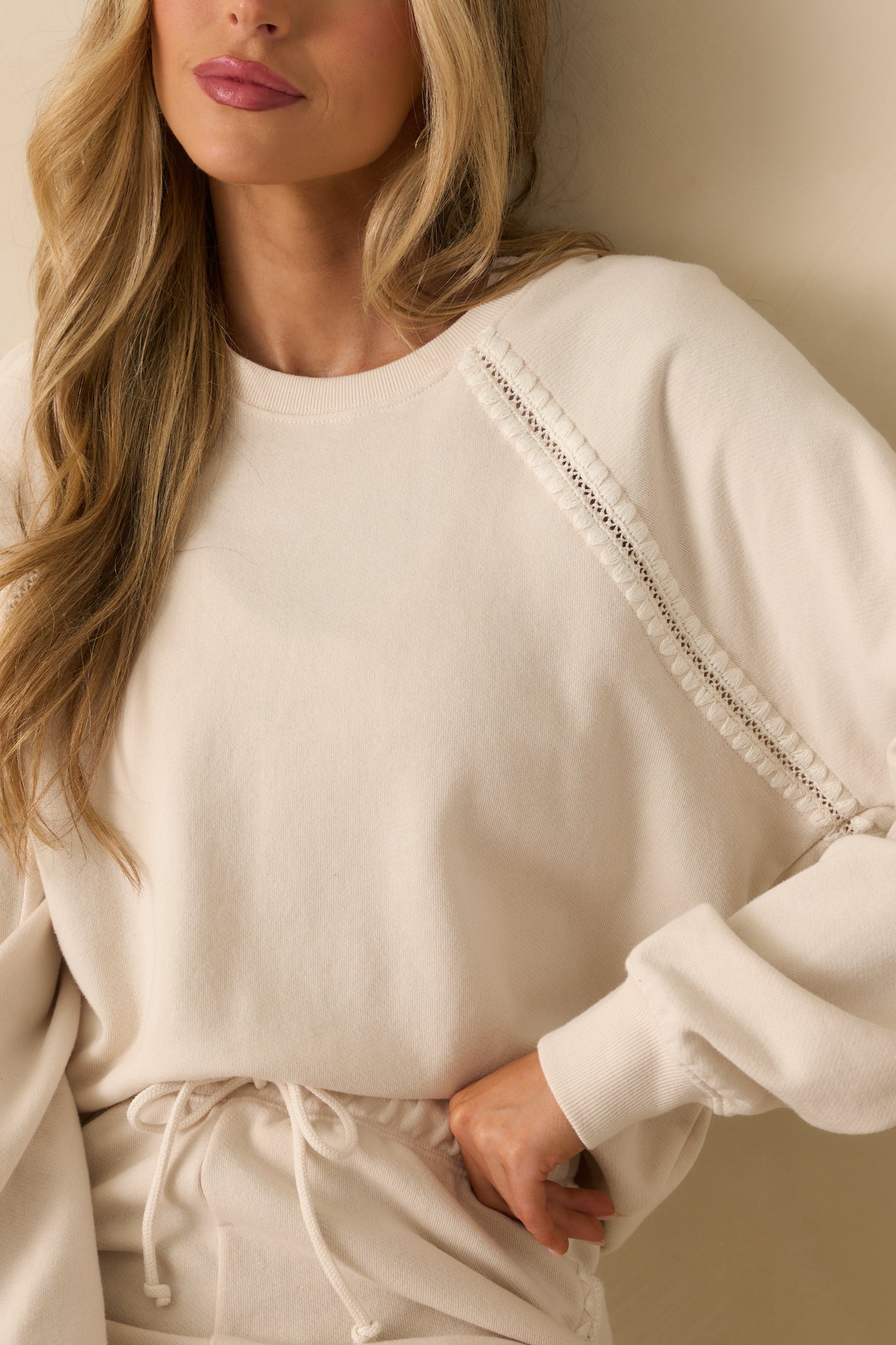 Detailed look at the embroidery and crochet accents on the raglan sleeve of the sweatshirt.