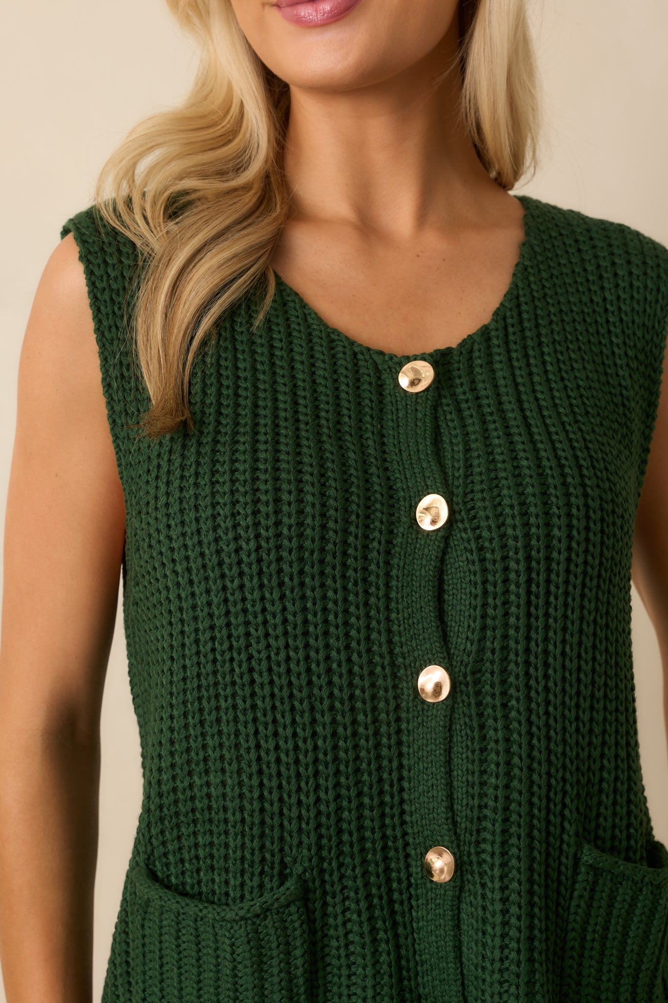 Detailed view of the hammered gold button front closure and ribbed knit fabric.