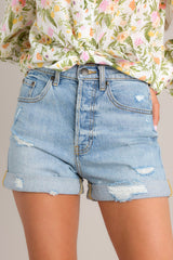 Close up front view of these light wash denim shorts that feature a high waist, classic button-zipper closure, functional belt loops, and five pockets.