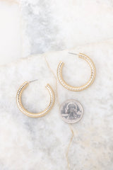 Size comparison view of these gold hoop earrings that feature a textured gold finish, and a secure post-back fastening.